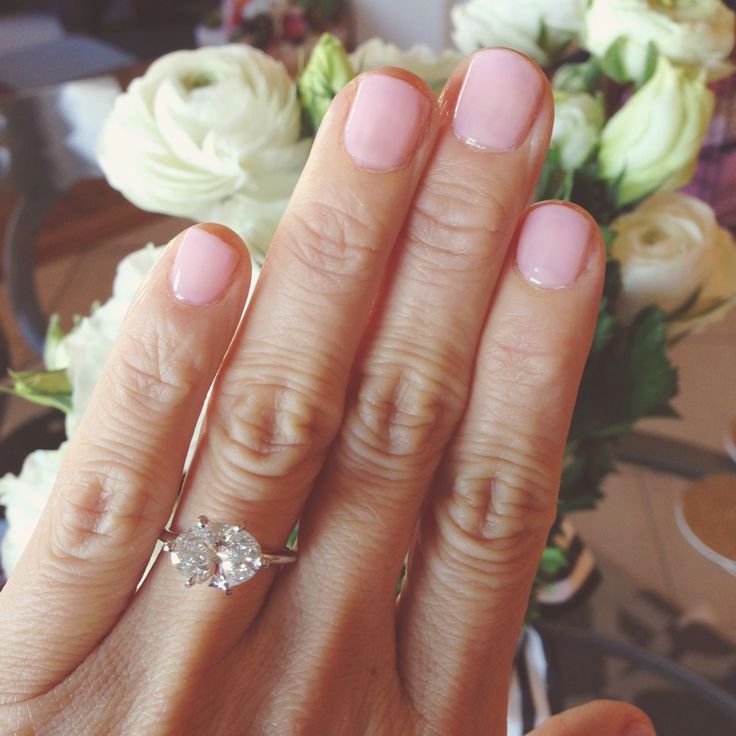 a close up of a person's hand with a diamond ring on their finger