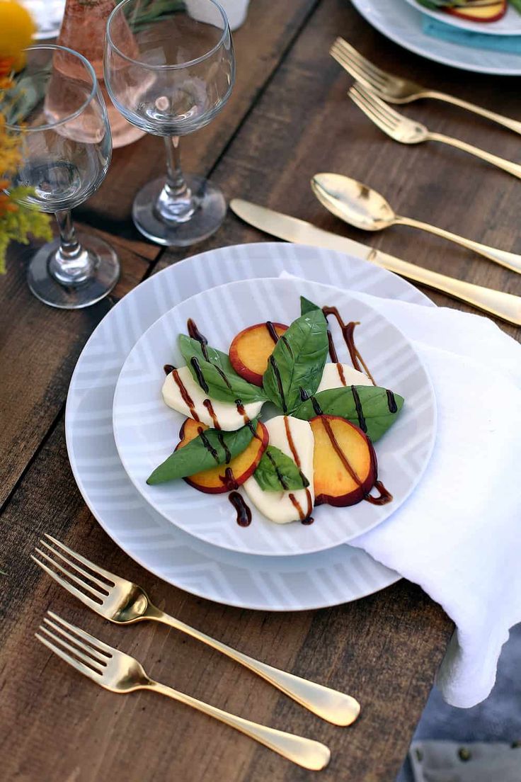 a white plate topped with sliced peaches on top of a wooden table next to silverware