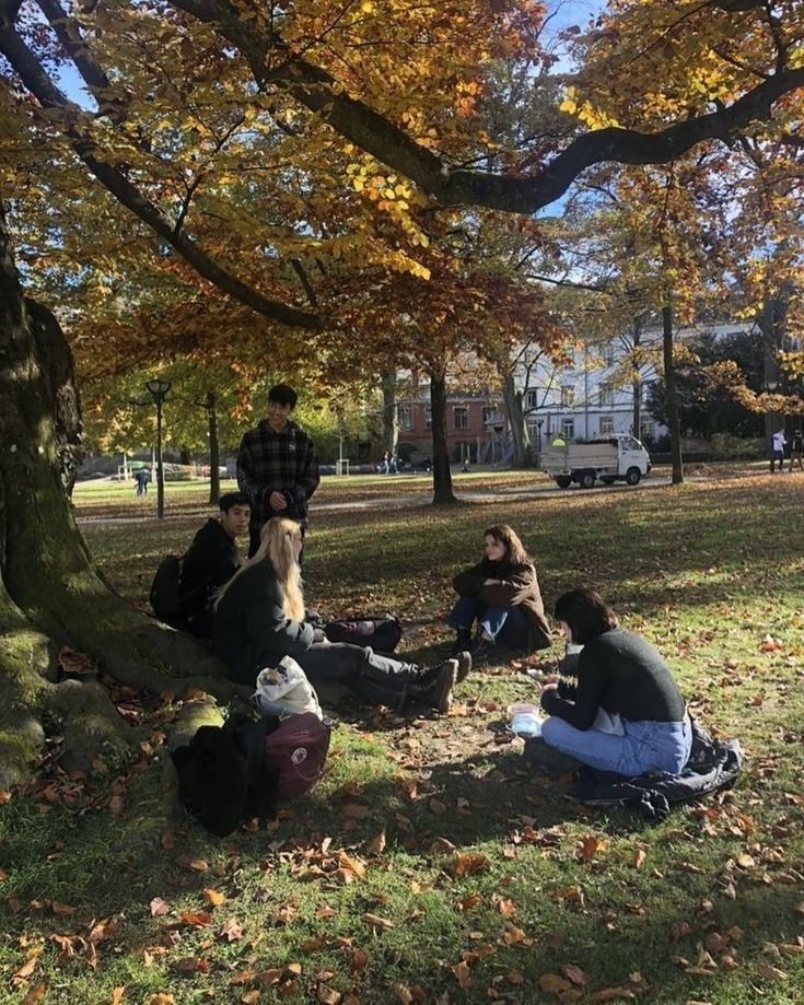 several people sitting on the ground under a tree