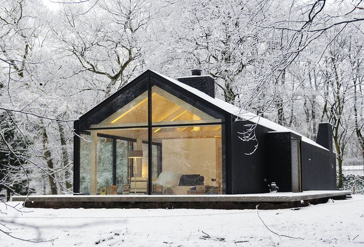 a small cabin in the middle of winter with snow on the ground and trees around it