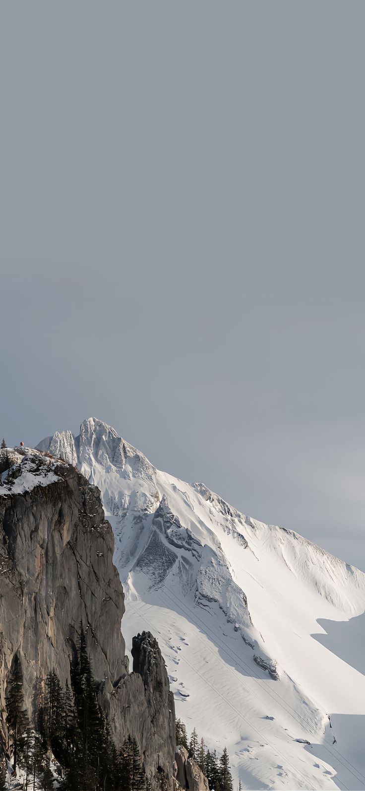 a person on skis is standing at the top of a mountain with mountains in the background