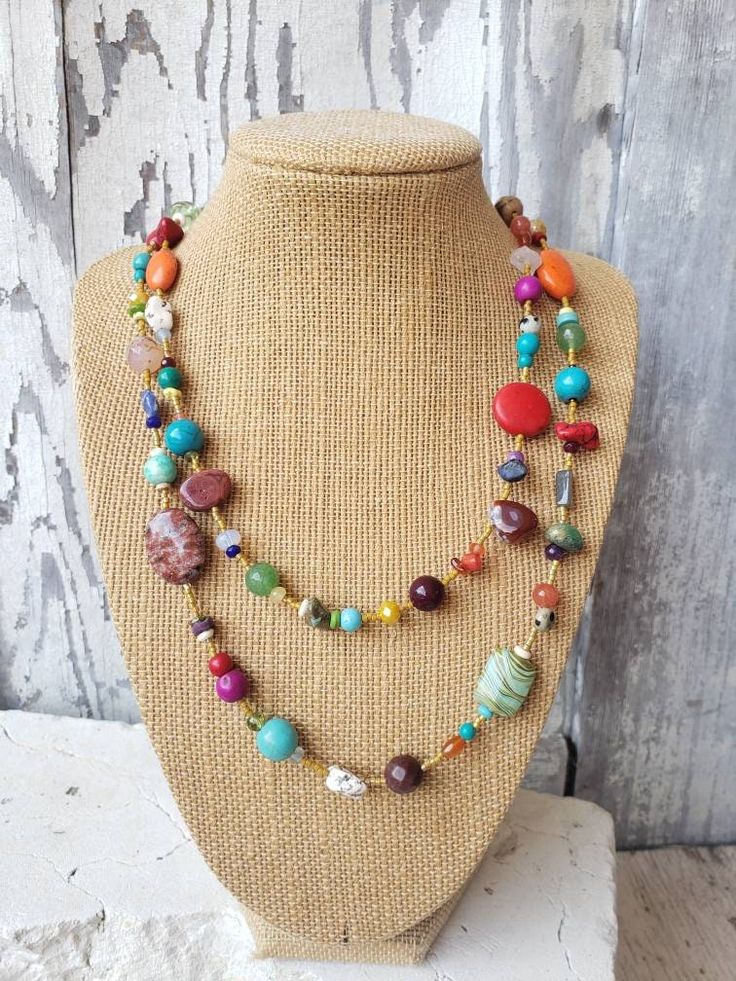 "Two pretty graduated strands of multi-color, semi precious stones make up this semi precious stone necklace.  Just about every stone you can imagine, turquoise, garnet, lapis lazuli, pearls, chrysoprase, red coral, and carnelian, just to name a few. In between the stones are cream/gold color Japanese seed beads. The necklace measures 18\" on the shortest length and 22\" on the longest length. Both  strands are connected with a large silver toggle clasp.  It is strung on an 18 strand nylon coate Bohemian Rainbow Necklaces With Natural Stones, Bohemian Rainbow Gemstone Beads Necklace, Colorful Bohemian Jewelry With Gemstone Beads, Bohemian Rainbow Beaded Necklaces With Natural Stones, Bohemian Rainbow Beaded Necklace With Natural Stones, Colorful Natural Stone Beaded Necklaces With Round Beads, Colorful Beaded Necklaces With Natural Stones, Bohemian Rainbow Gemstone Beaded Necklace, Colorful Bohemian Necklaces With Natural Stones