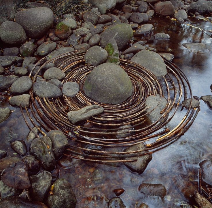 a metal circle sitting on top of rocks near water