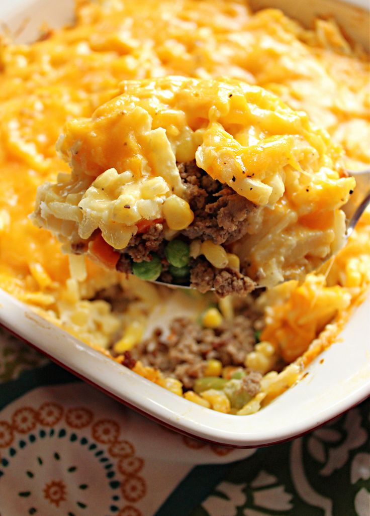 a spoon full of macaroni and cheese is being lifted from the casserole dish