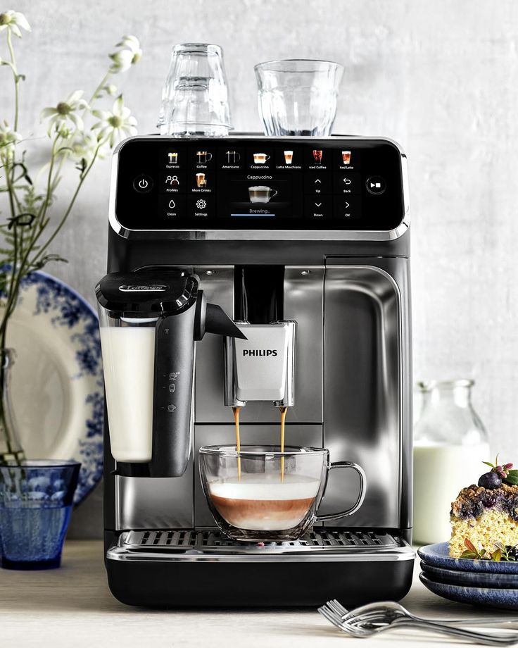 an espresso machine with milk being poured into it and on the counter next to plates