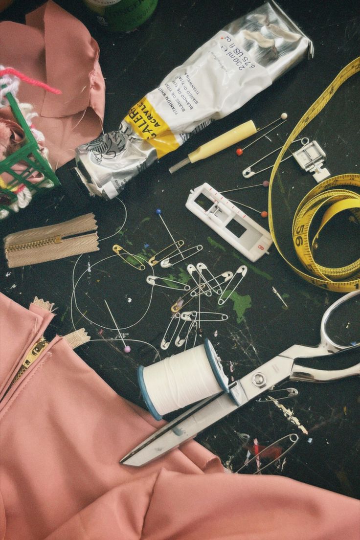 the contents of a sewing project laid out on top of a black table with scissors, thread, and other items