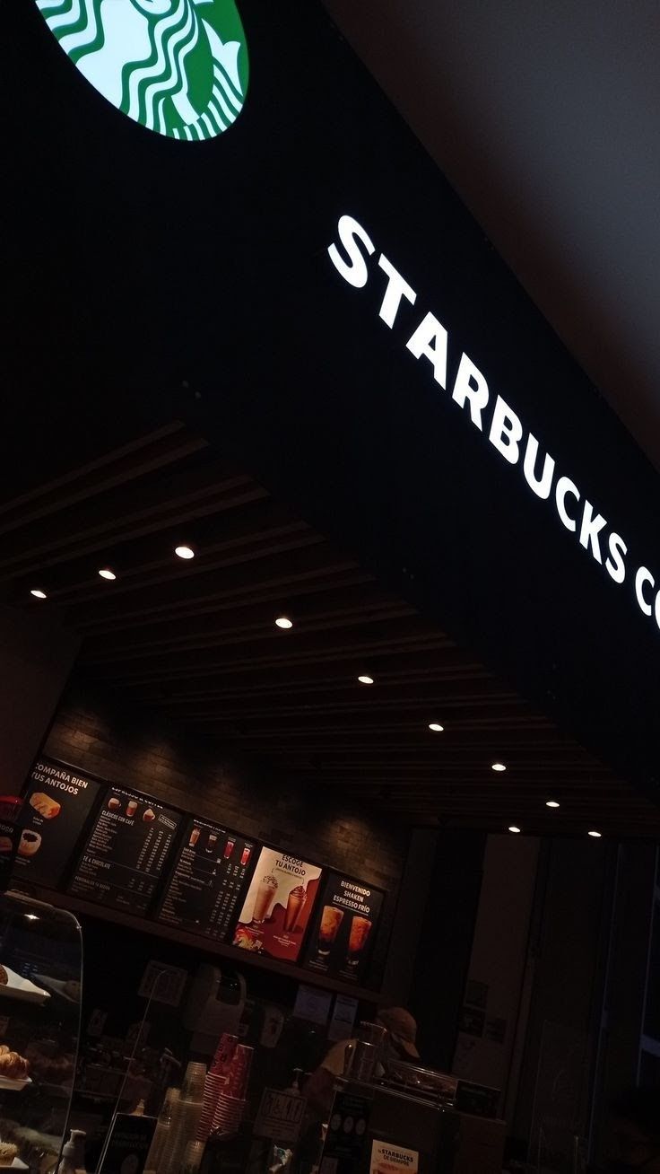 the starbucks sign is lit up at night