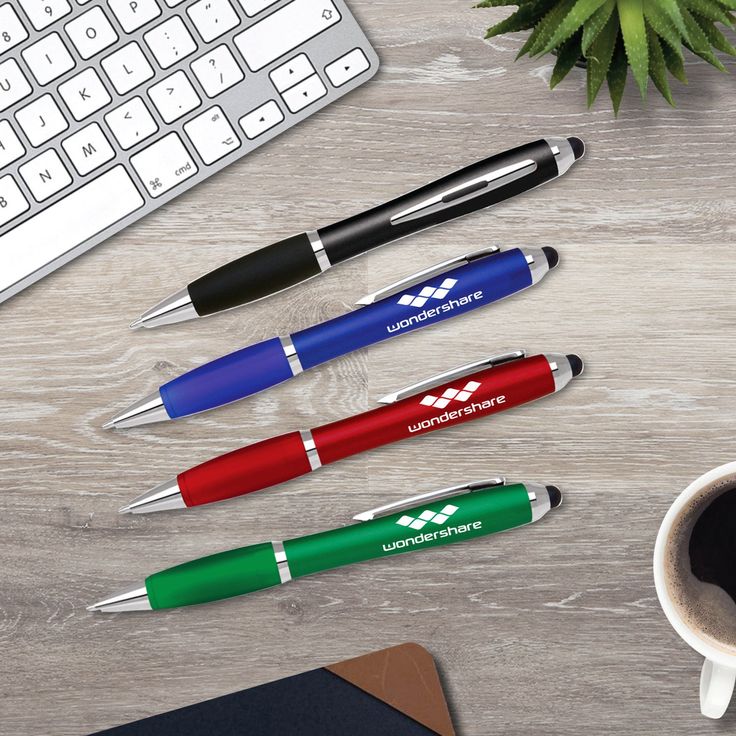 four different colored pens sitting on top of a desk next to a keyboard and mouse