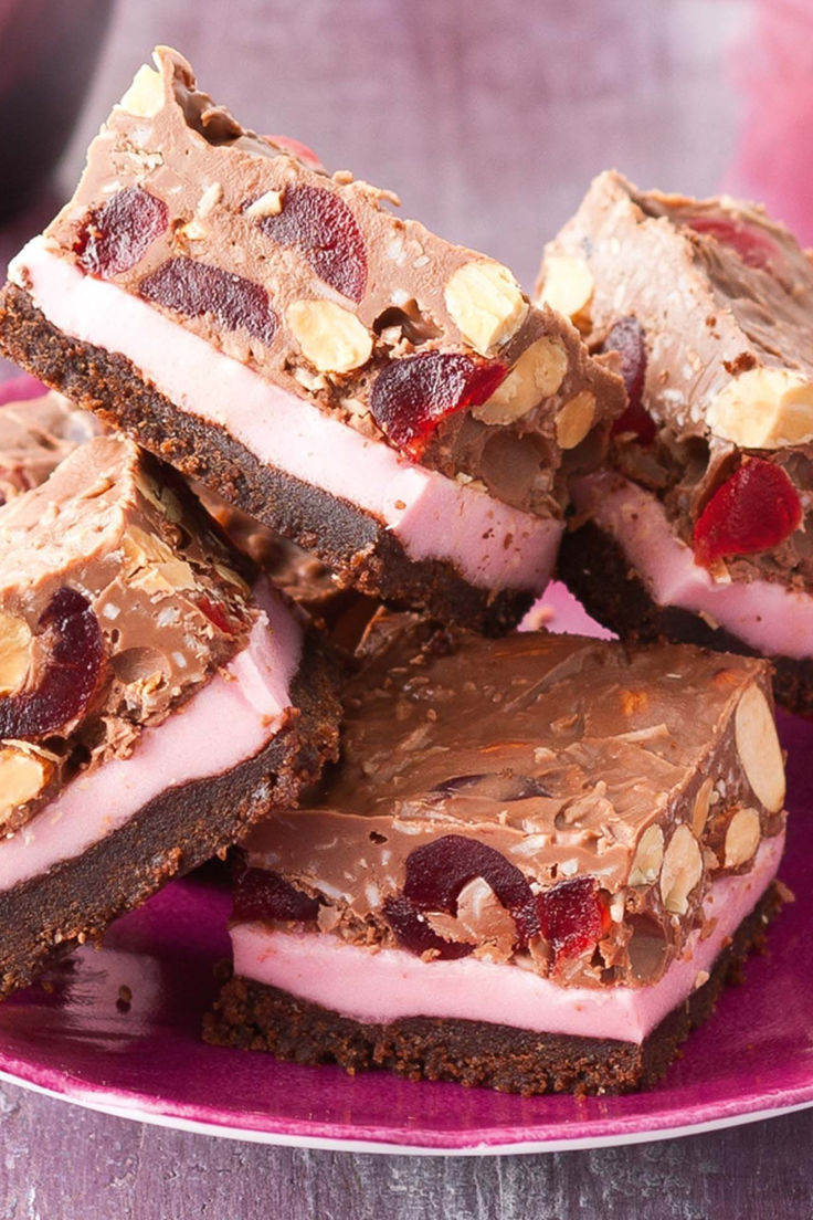 a pink plate topped with pieces of chocolate and candy bar desserts on top of each other