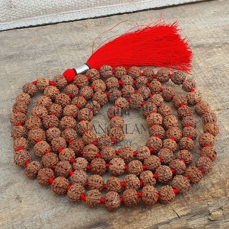 a red tasseled beaded necklace on top of a piece of wood