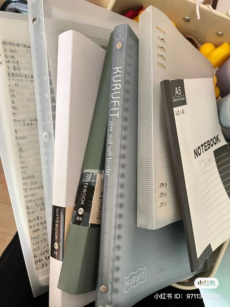 several folders are stacked on top of each other in a file box, with pens and pencils next to them