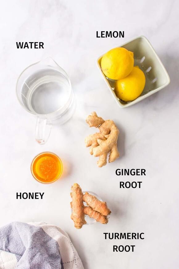 lemons, ginger root, turmeric root and water on a white surface