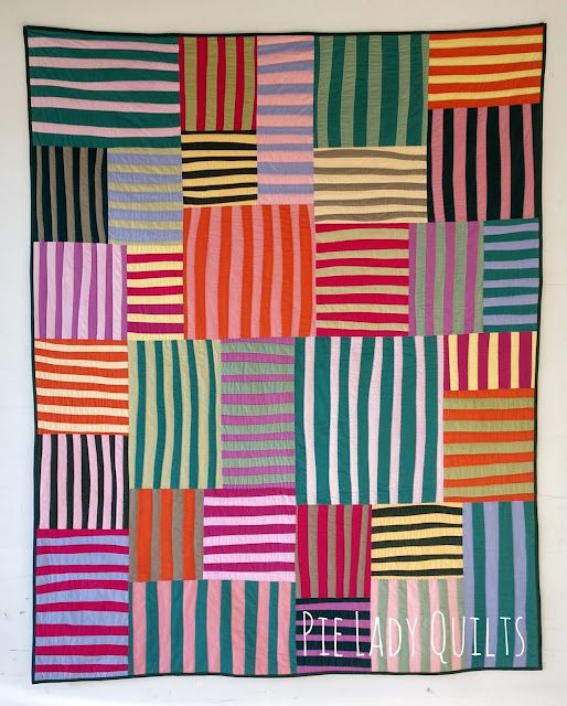 a multicolored patchwork quilt hanging on a wall