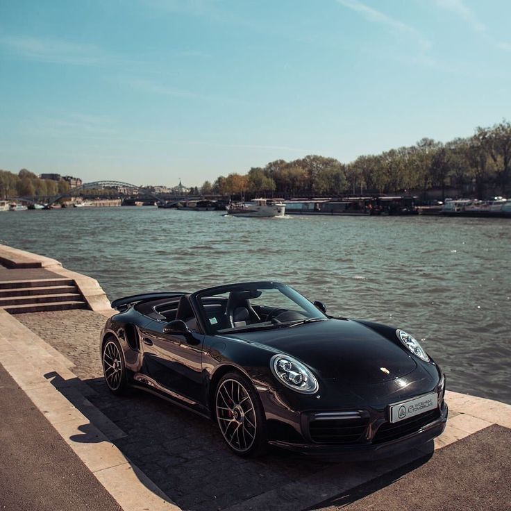 a black sports car parked next to the water