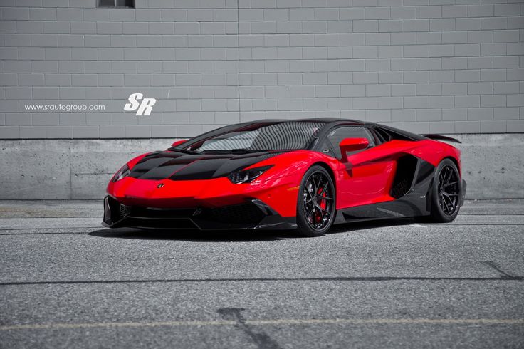 a red and black sports car parked in front of a brick wall