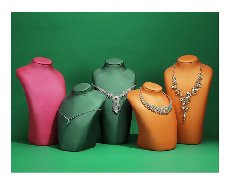 three different colored vases with necklaces on them in front of a green background