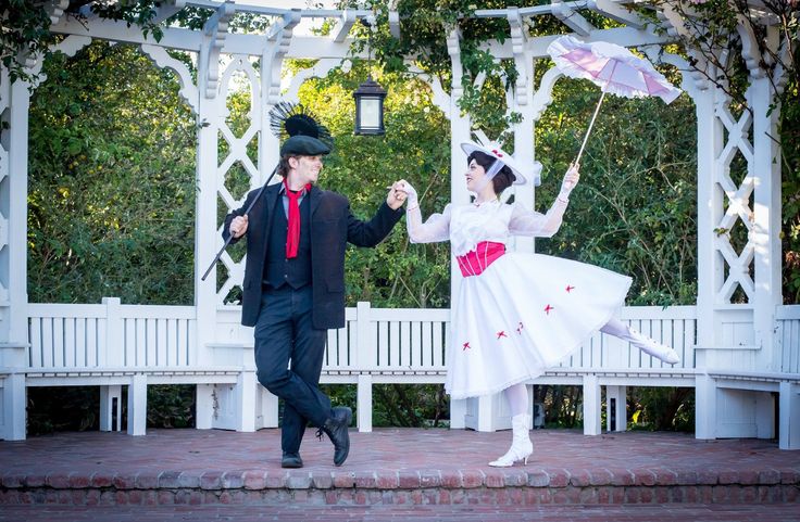 a man and woman dressed up in costumes dancing on steps under an arbor with an umbrella