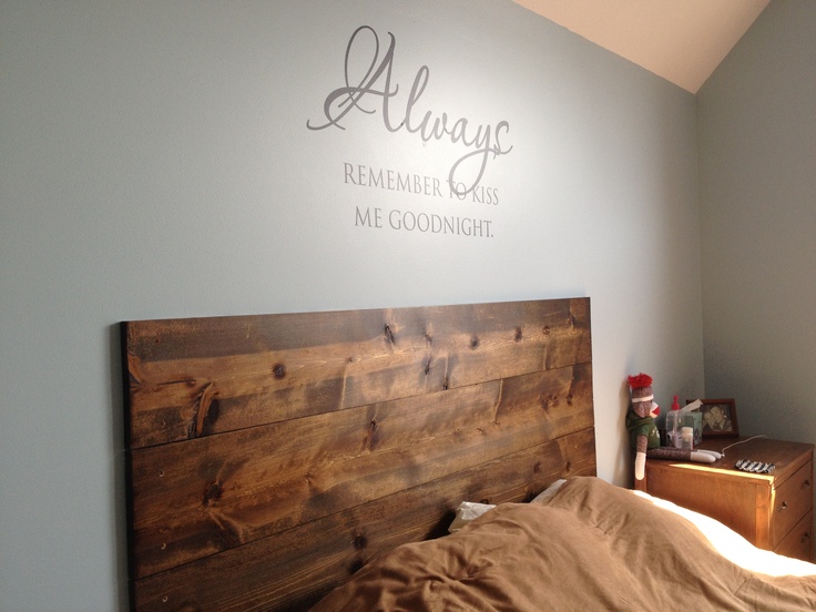 a bed with a wooden headboard in a bedroom next to a wall that says always