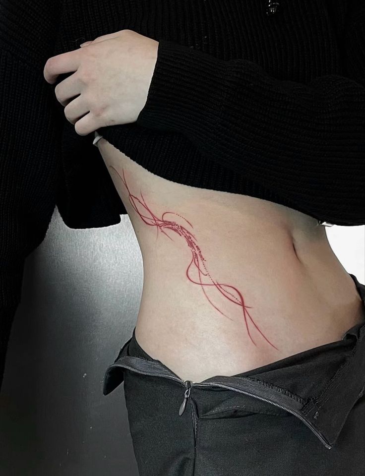 a woman's stomach with a red tattoo on her lower body and the bottom part of her abdomen