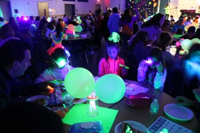 a large group of people sitting at tables in a room with green and blue lights