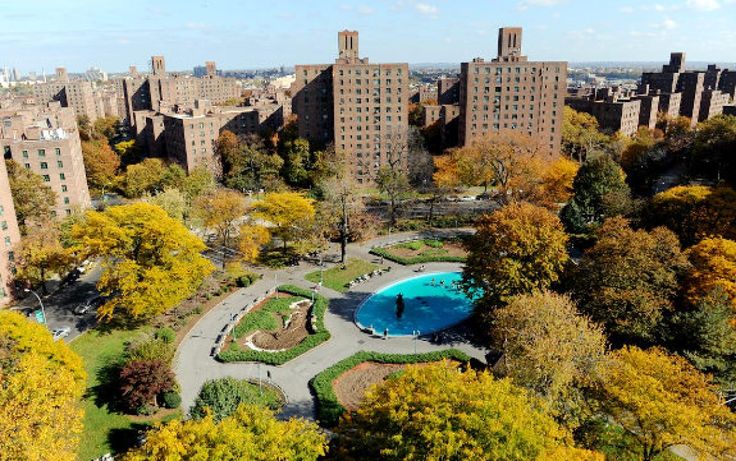 an aerial view of a park with trees, buildings and a pool in the middle