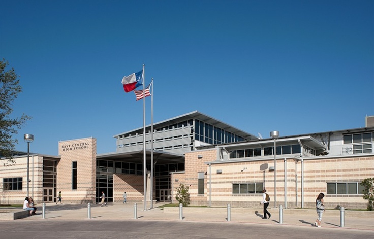 two people walking in front of a building with an american flag on the top of it