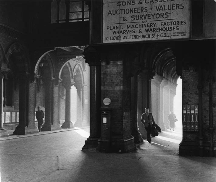 an old black and white photo of a man walking down the street