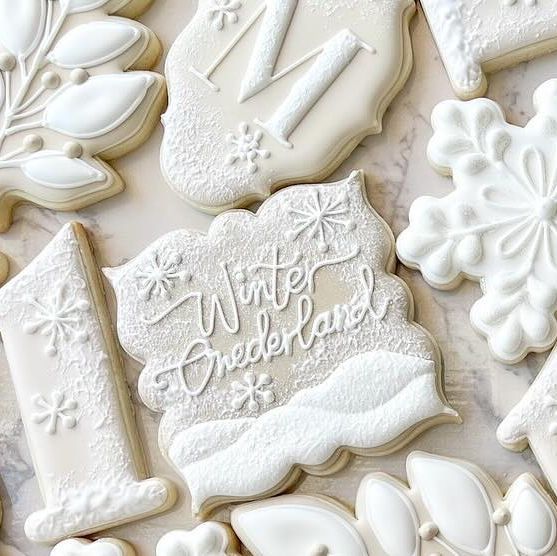 decorated cookies with frosting and icing are arranged on a tablecloth that says winter wonderland