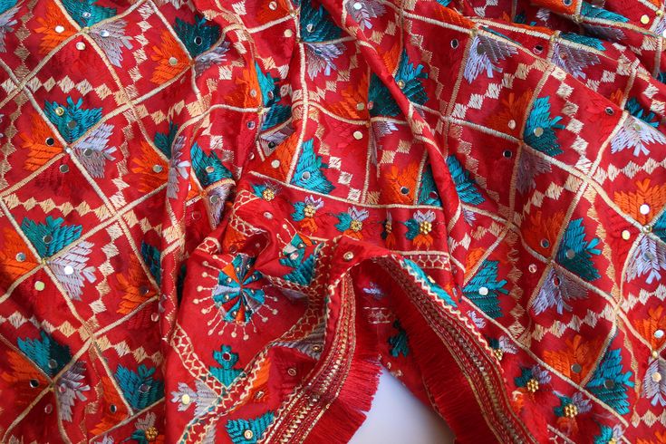 Phulkari refers to the folk embroidery of the Punjab. Although phulkari means floral work, the design include not only flowers but also covers motifs and geometrical shapes. The craft of phulkari has undergone changes over the centuries. This gorgeous colorful phulkari on pure chinnon in red color is so versatile and can be worn as a dupata, scarf or on any wedding occasion. Our phulkaris are handcrafted to perfection keeping in mind the authenticity of the culture in an urban way. Stand out with this intricately designed phulkari.  ALL SALES ARE FINAL !! Festive Traditional Wear With Resham Embroidery For Rituals, Multicolor Fabric With Resham Embroidery For Festive Occasions, Multicolor Resham Embroidery Fabric For Festive Occasions, Multicolor Banarasi Silk Fabric With Zari Work For Navratri, Multicolor Festive Fabric For Navratri, Festive Multicolor Fabric With Resham Embroidery, Embroidered Traditional Wear For Eid Rituals, Festive Multicolor Resham Embroidery Fabric, Embroidered Dupatta For Eid Rituals