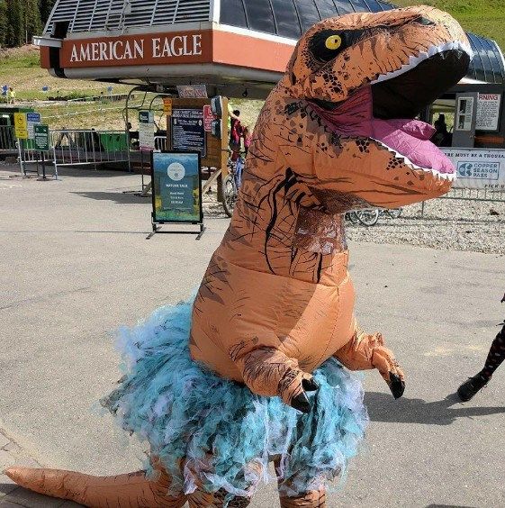 an inflatable dinosaur costume is standing on the sidewalk