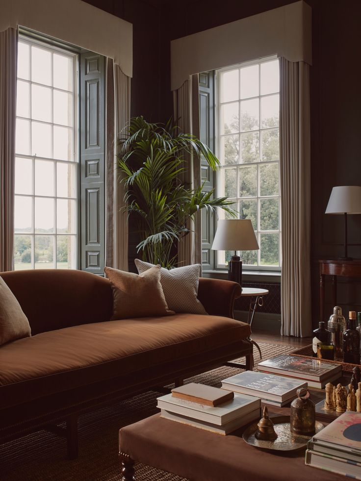 a living room filled with lots of furniture next to two large windows and a coffee table