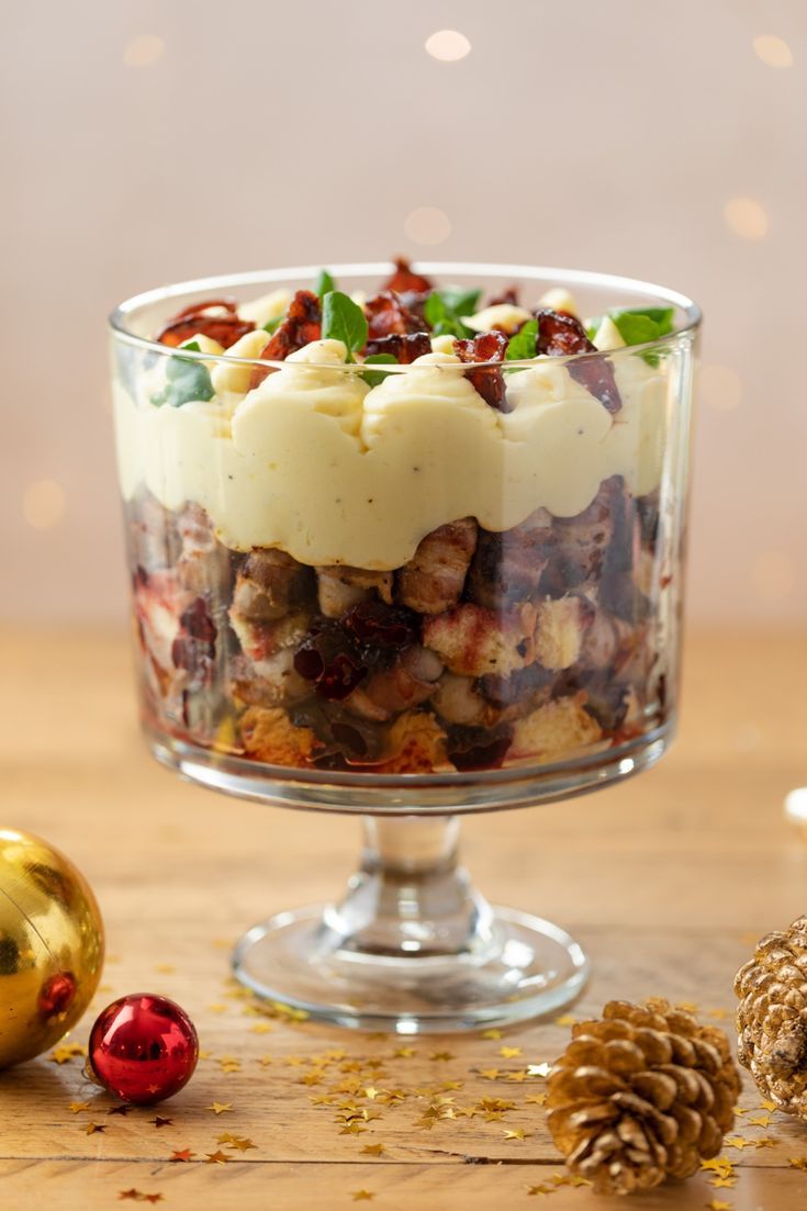 a glass bowl filled with food on top of a wooden table next to christmas decorations