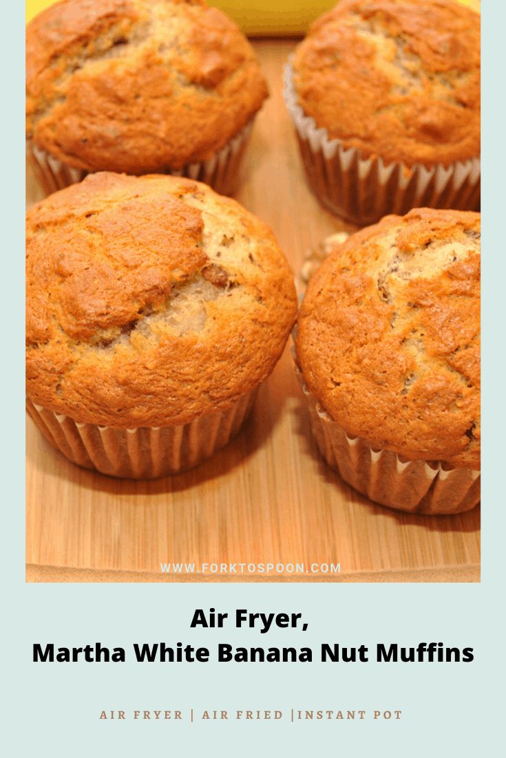 four banana muffins sitting on top of a wooden cutting board