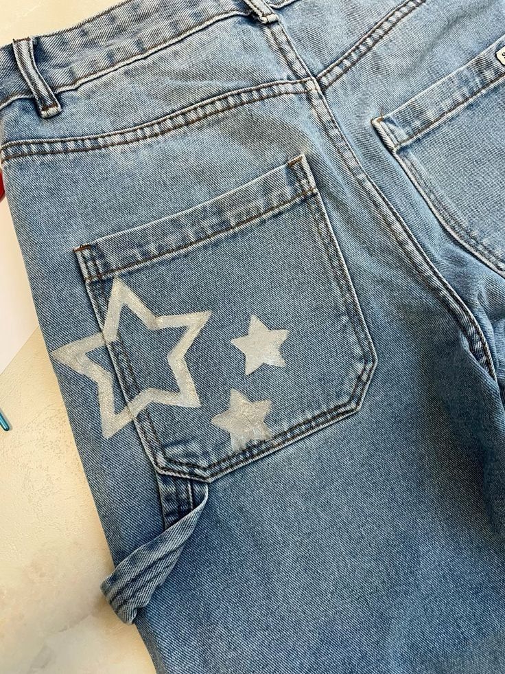 a pair of blue jeans with white stars on the front and back pockets, sitting on a table