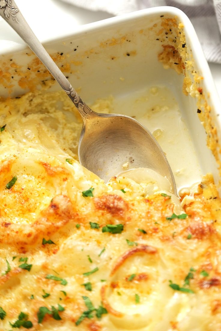 a casserole dish with cheese and parsley on the side, ready to be eaten