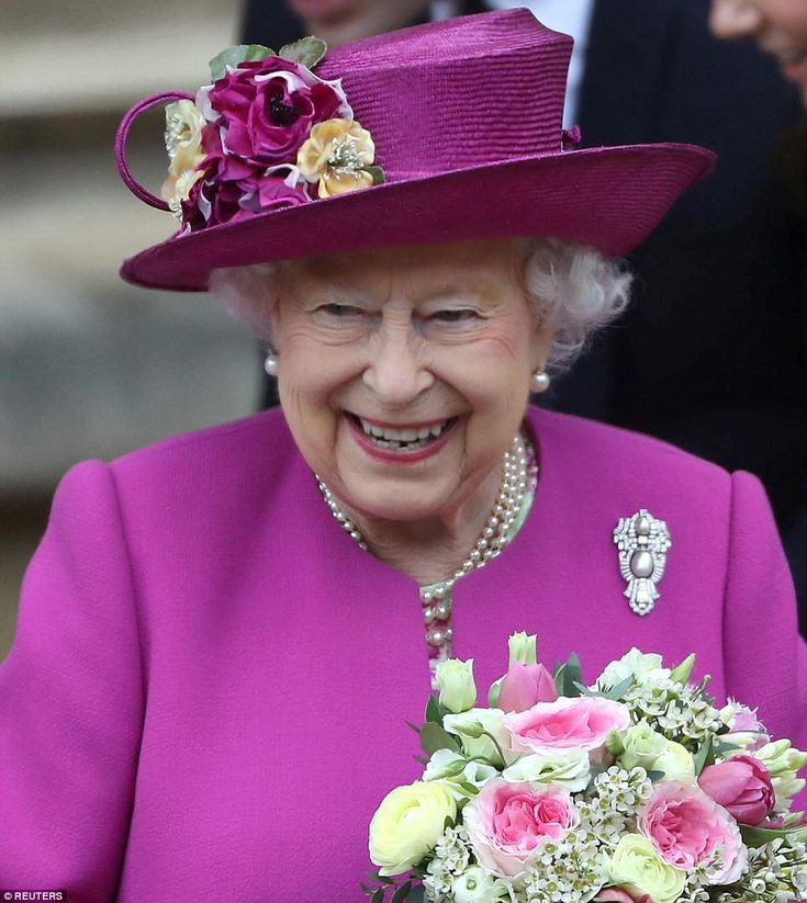 the queen smiles as she holds a bouquet of flowers