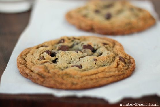 three chocolate chip cookies sitting on top of white paper