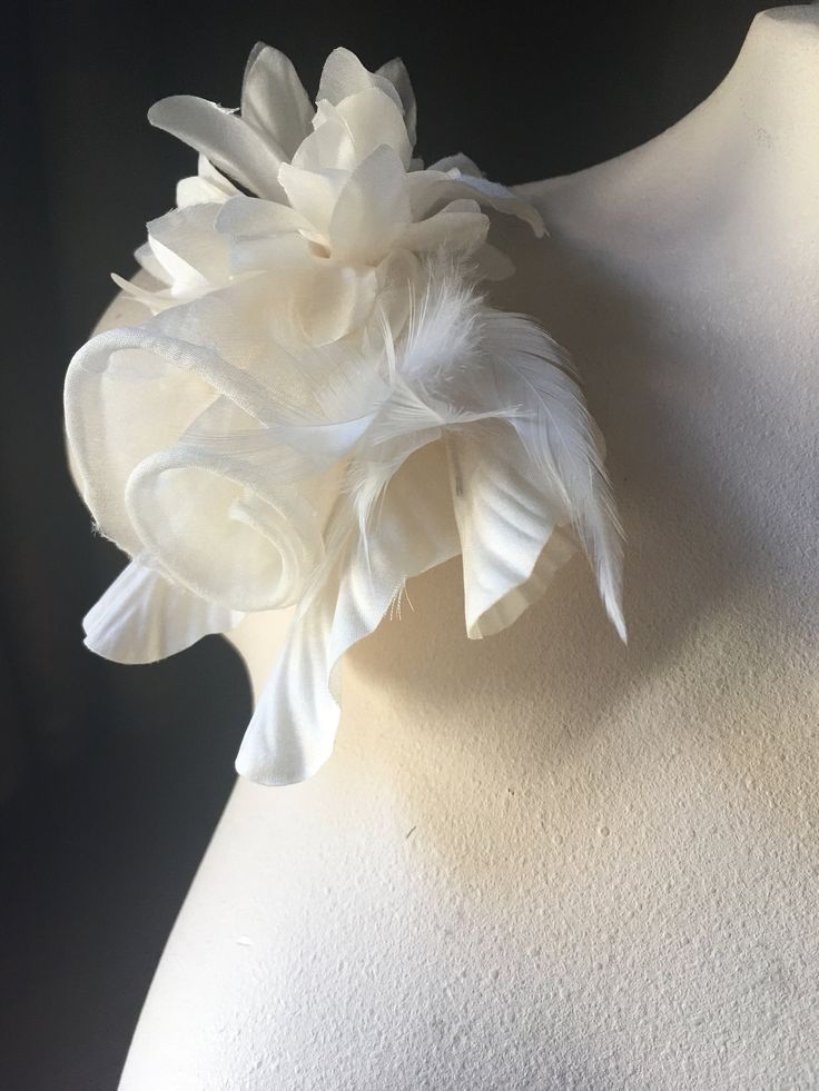 a white flower is on top of a mannequin's neckline with feathers