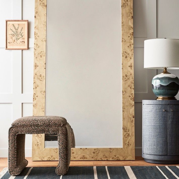 a large mirror sitting on top of a wooden floor next to a chair and lamp