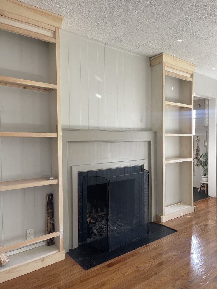 an empty living room with a fireplace and bookcases