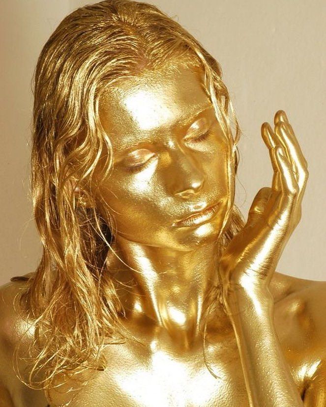 a close up of a gold colored statue holding her hands to her face and eyes