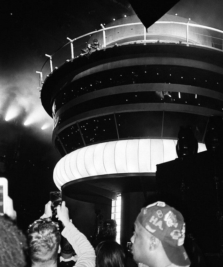 black and white photograph of people standing in front of a building at night with lights on