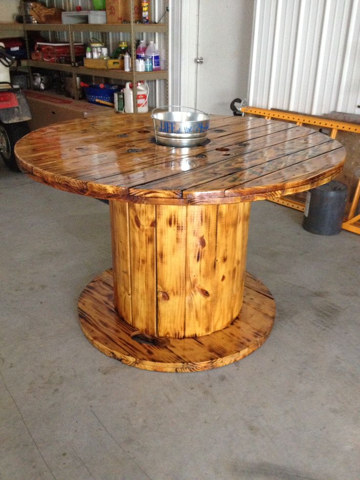 a wooden table sitting inside of a garage next to a metal bowl on top of it