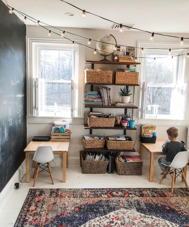 a boy sitting at a desk in front of a blackboard with books on it