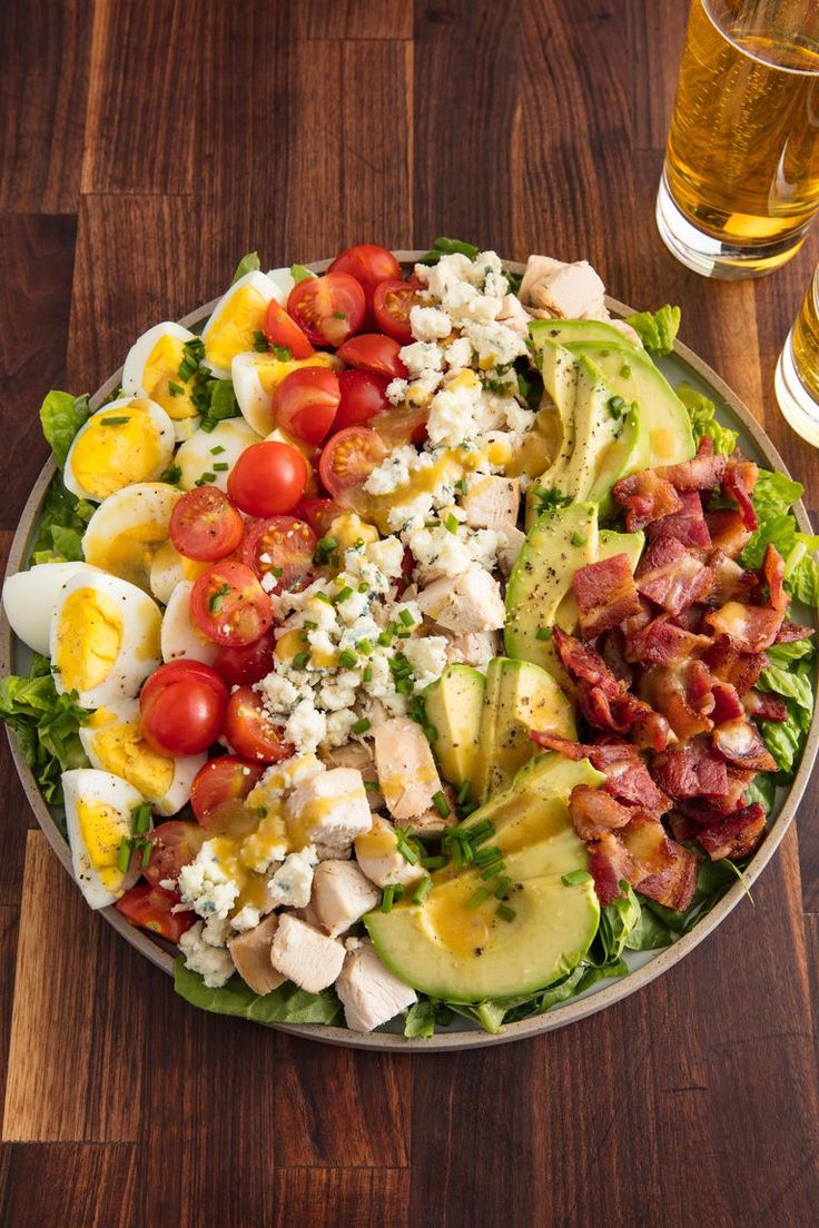 a salad with bacon, tomatoes, avocado and hard boiled eggs on it