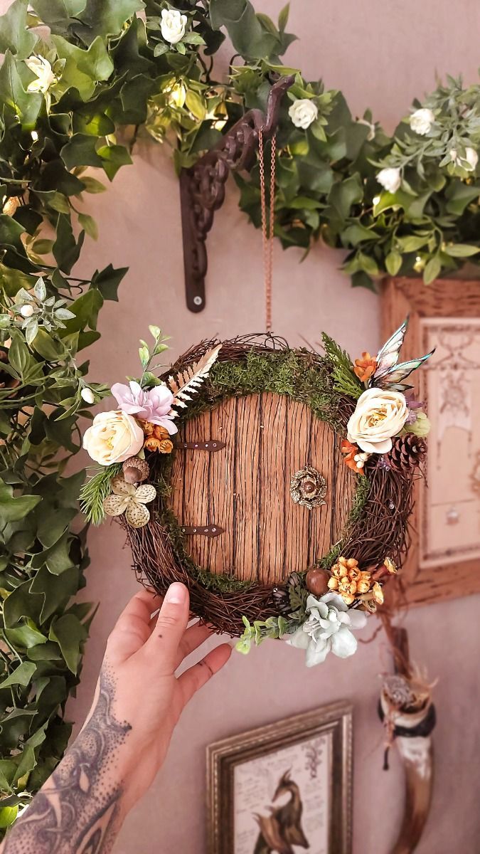 a person holding up a wreath with an image of a door in the middle and flowers around it