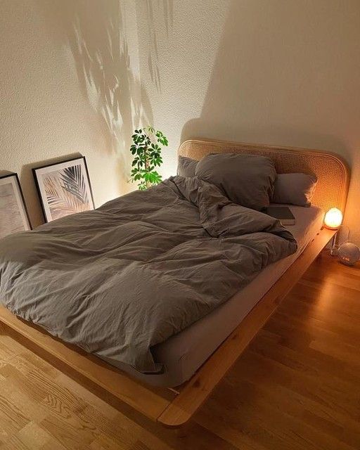 a bed sitting on top of a wooden floor next to a lamp