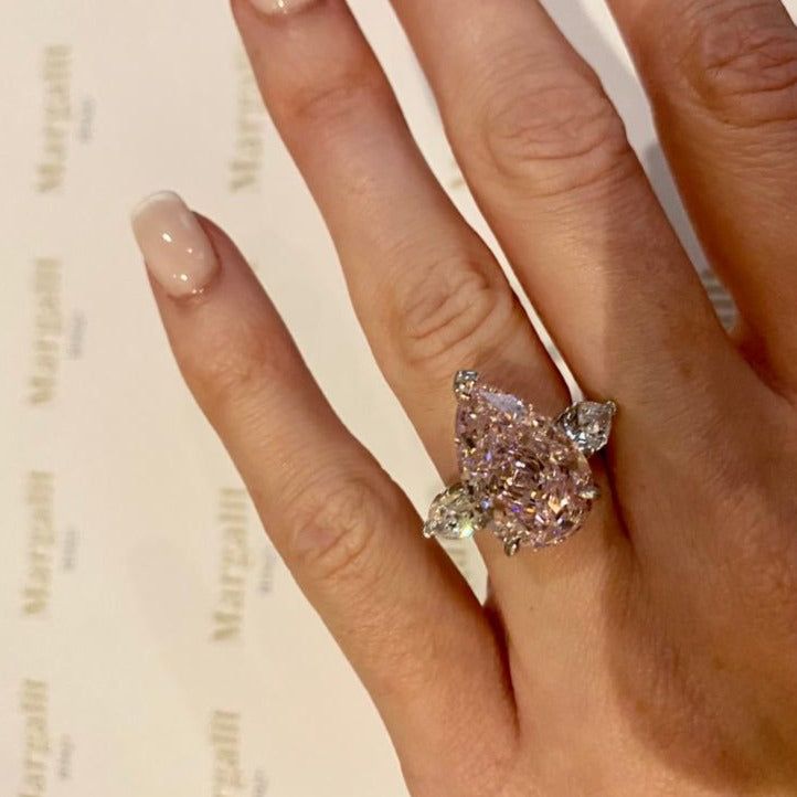 a woman's hand with a ring on top of it and a book in the background