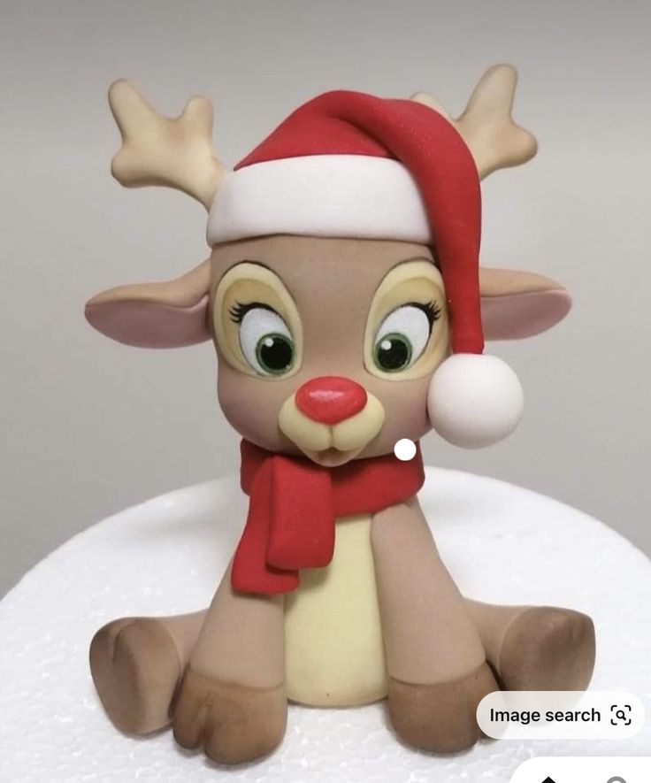 a close up of a cake with a reindeer on it's head and scarf