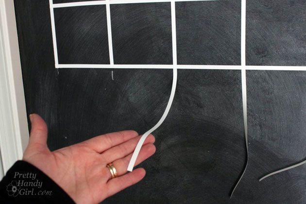 a hand holding a string attached to a blackboard with squares and lines drawn on it